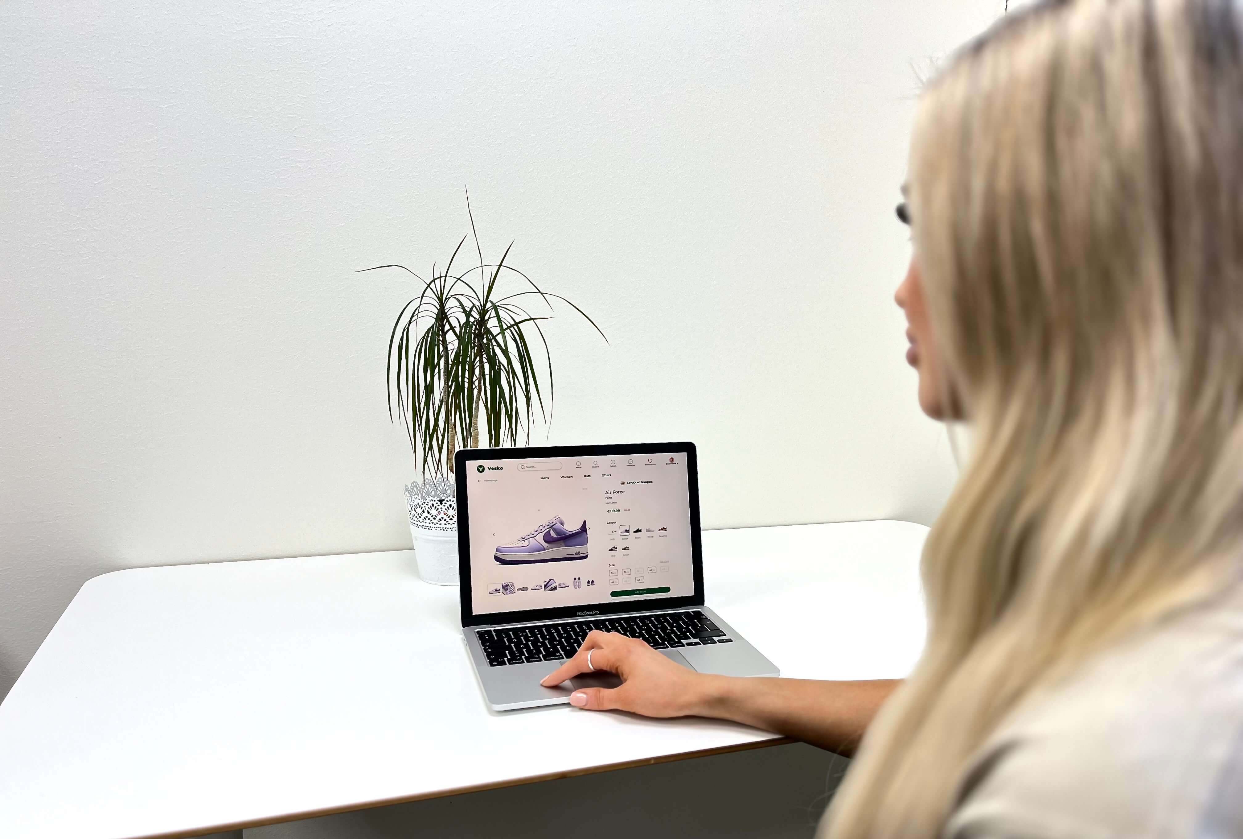 Lady focused on a laptop screen displaying Vesko's product details page, highlighting her engagement in online shopping for unique products.