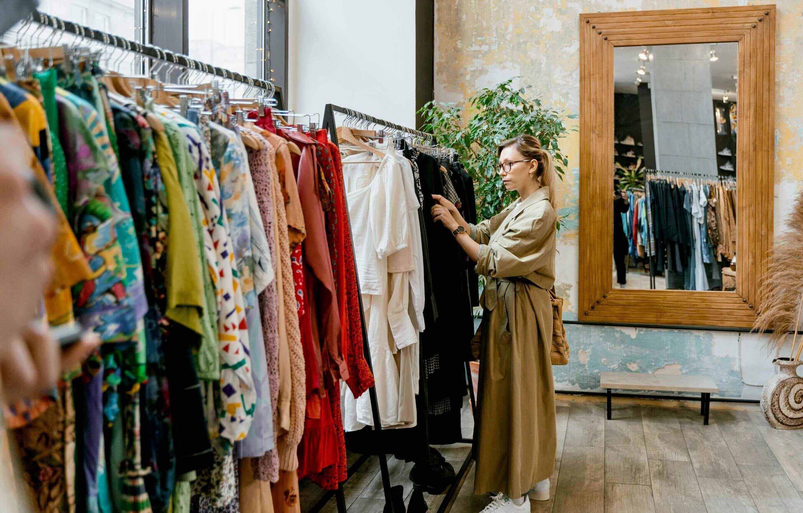 An employee organizing clothing on shelves and hangers in a retail environment, showcasing a well-maintained vendor space for an optimal shopping experience.